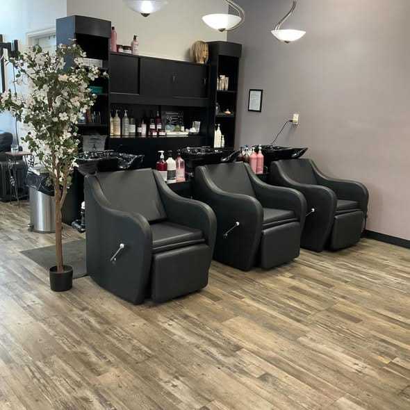 Three salon chairs with hair washing stations and product shelves.